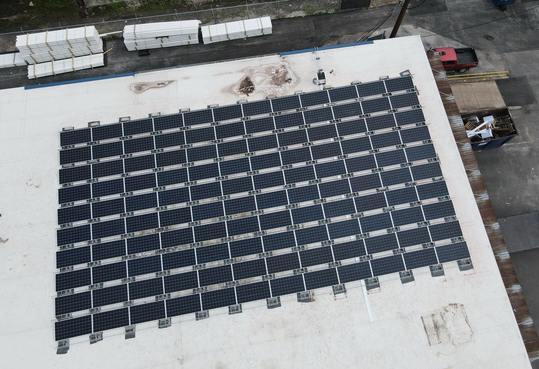 Grid of solar panels on the white flat roof of the Wells Plumbing building in Houston